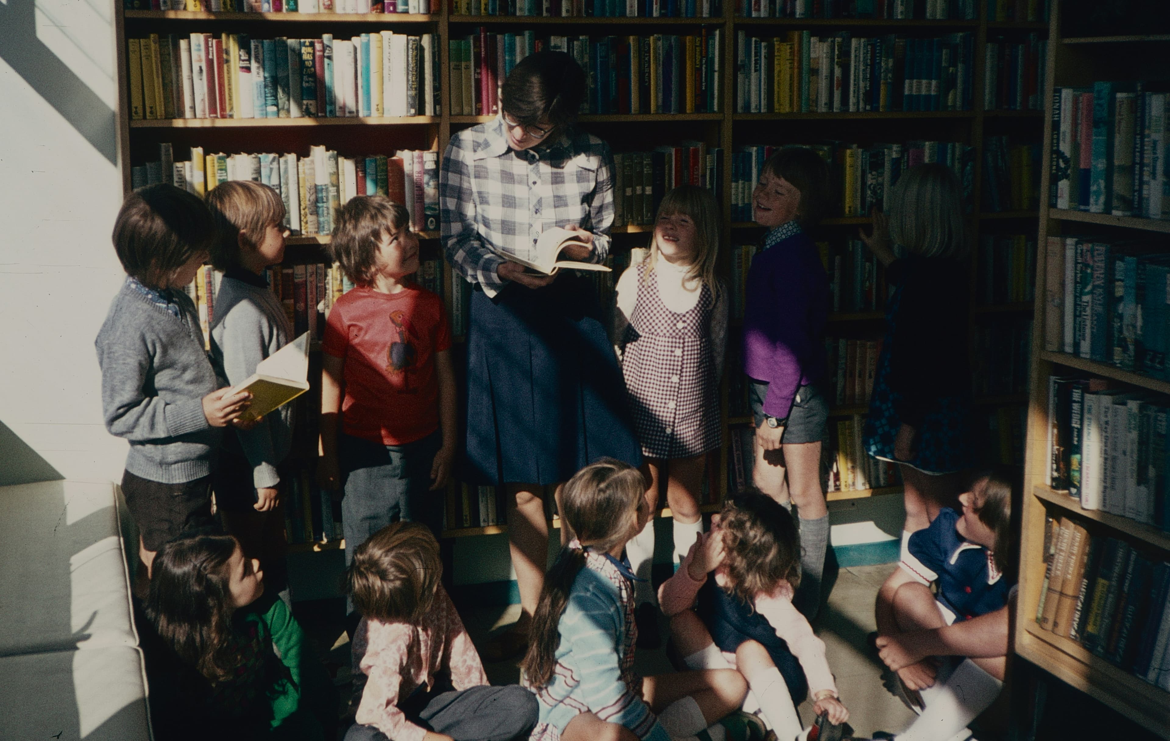 A group of children gathered around a teacher reading together
